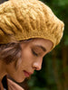 Person wearing a yellow knitted hat with a blurred natural background